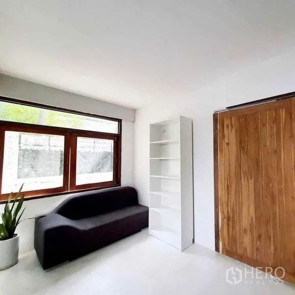 Detached House for rent in Pathum Wan, Bangkok - Bright bedroom or study with large window, black sofa, white shelving and wood sliding door