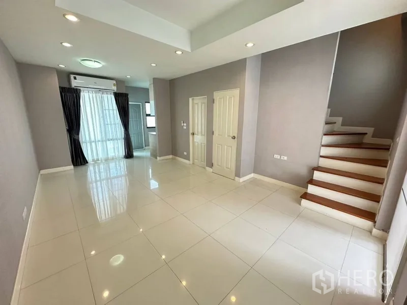 ทาวน์เฮาส์ ให้เช่าหรือขายในPhra Khanong, Bangkok - ห้องนั่งเล่นชั้นล่างปูกระเบื้องสีขาว ฝ้าดรอปไลท์ และทางขึ้นบันได