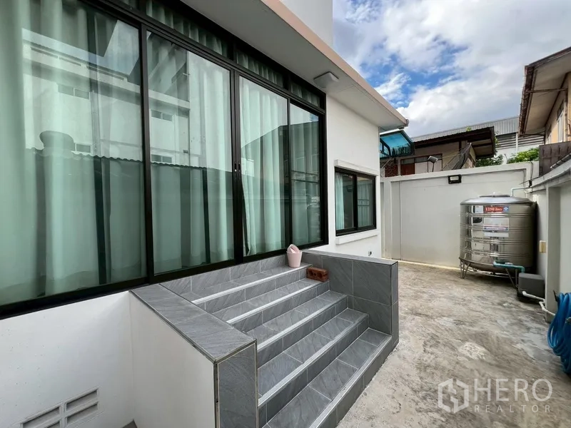 บ้าน ขายในPhra Khanong, Bangkok - ลานหลังบ้านมีประตูกระจกบานเลื่อน บันได และแทงก์น้ำสแตนเลส