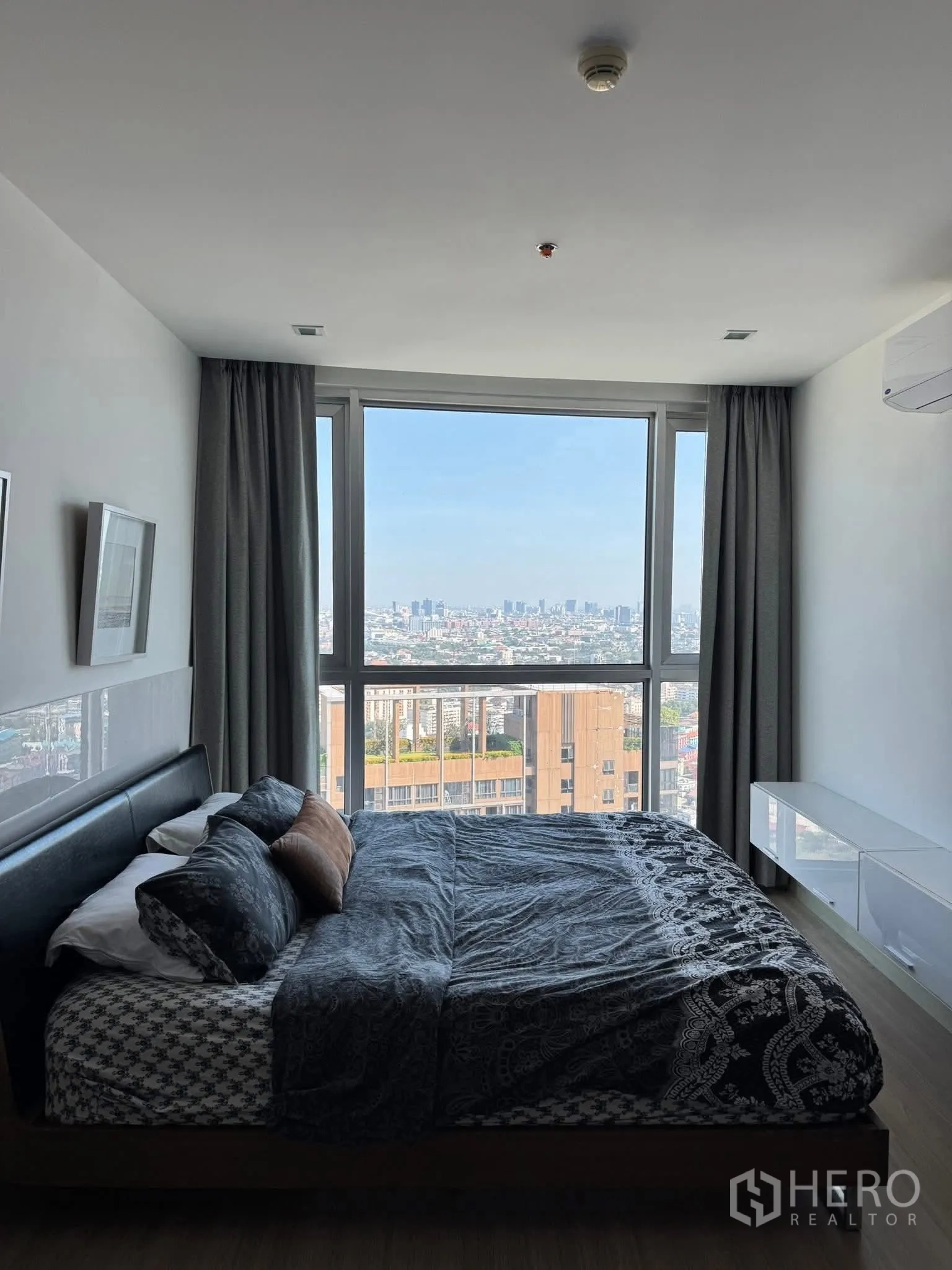 Condominium for rent in Watthana, Bangkok - Bedroom with large window and skyline view, double bed, and air conditioner.