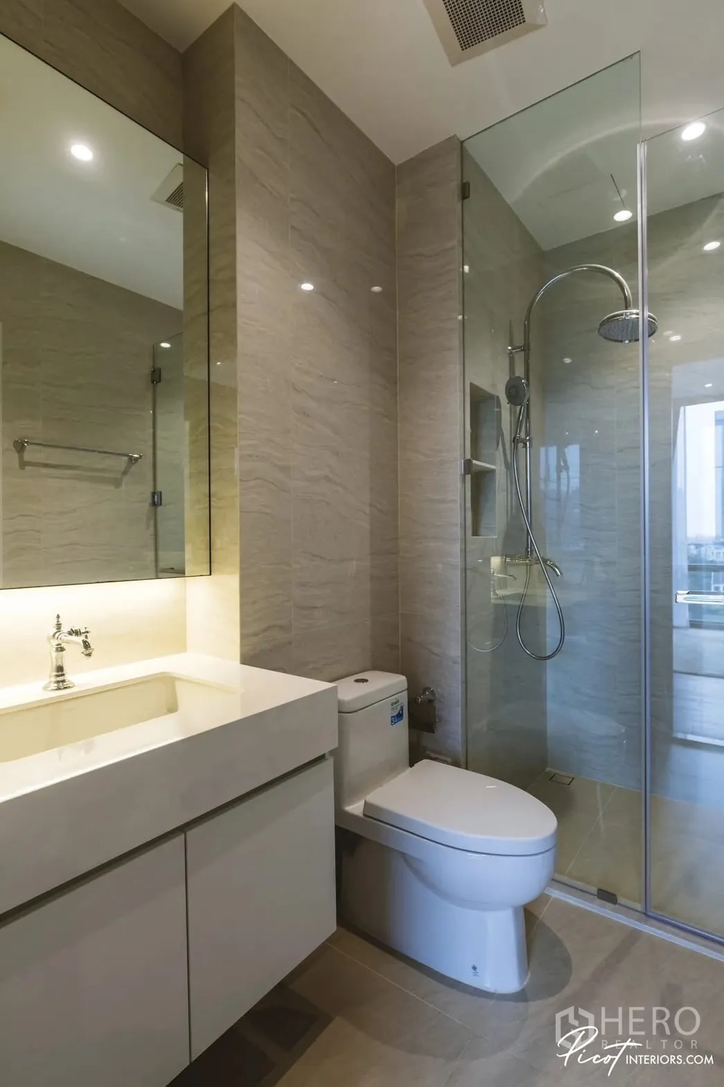 Condominium for rent in Pathum Wan, Bangkok - Modern bathroom with glass-enclosed rain shower, large mirror cabinet, and sleek vanity.