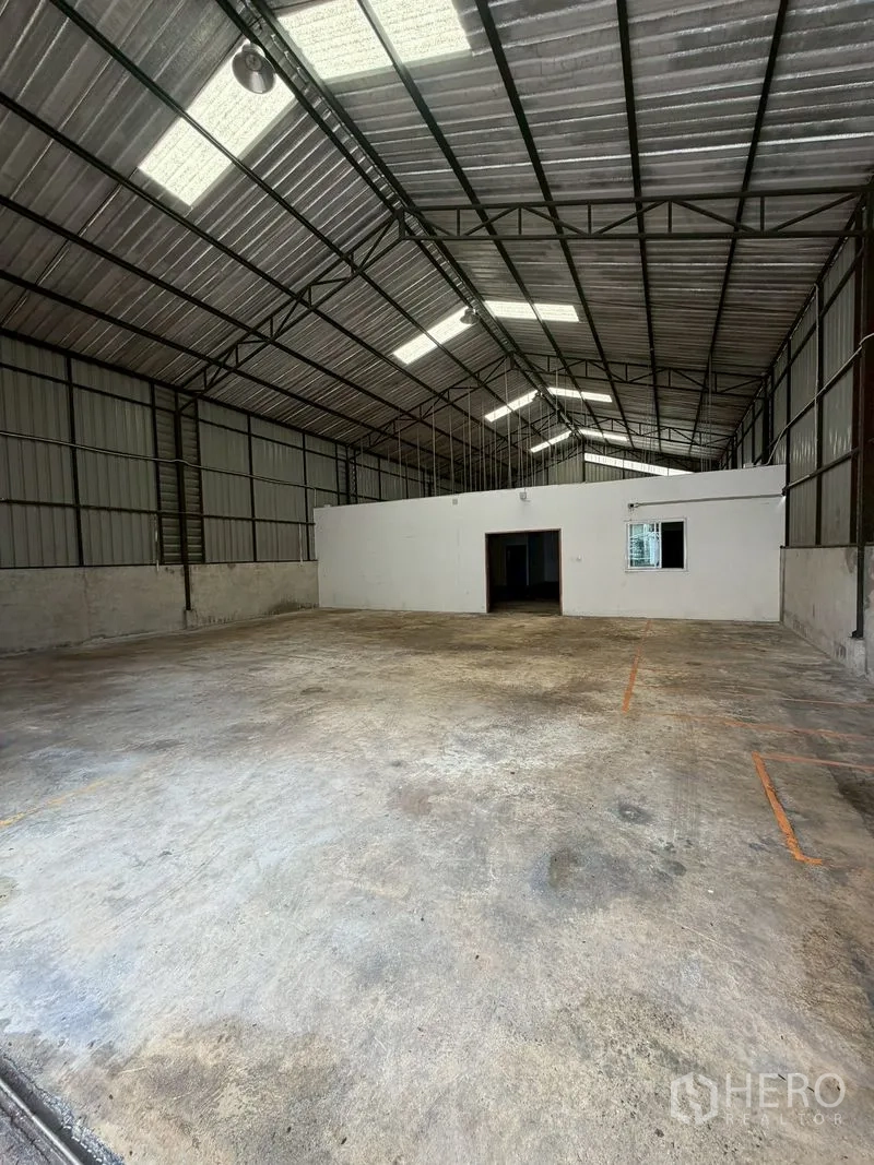 Warehouse for rent in Lat Phrao, Bangkok - Wide warehouse bay with truss roof and a partitioned room at the rear.