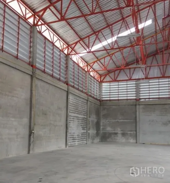Warehouse for rent in Khlong Sam Wa, Bangkok - High-clearance warehouse interior with red steel trusses, louvered ventilation, and smooth concrete floor.