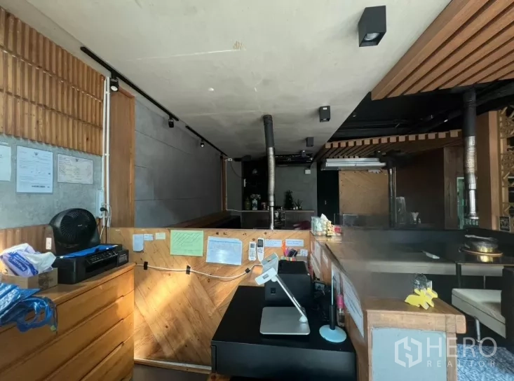 零售空间 出租在Watthana, Bangkok - 木质服务吧台与收银设备，面向开放式就餐区与通风管道。