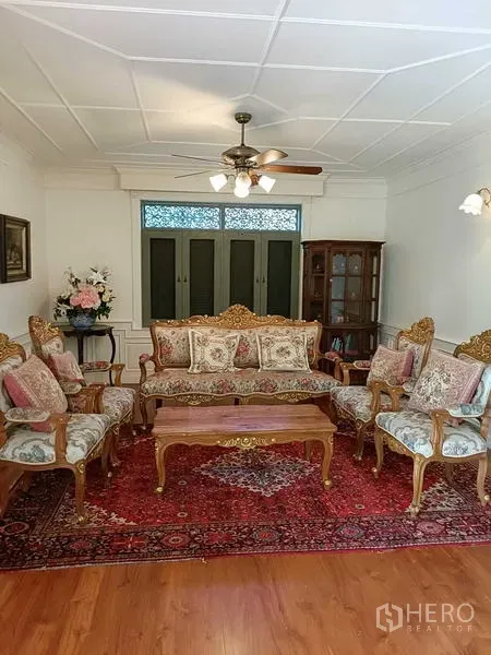 Detached House for rent or sale in Krathum Baen, Samut Sakhon - Formal living room with ornate sofa set, ceiling fan and patterned rug.