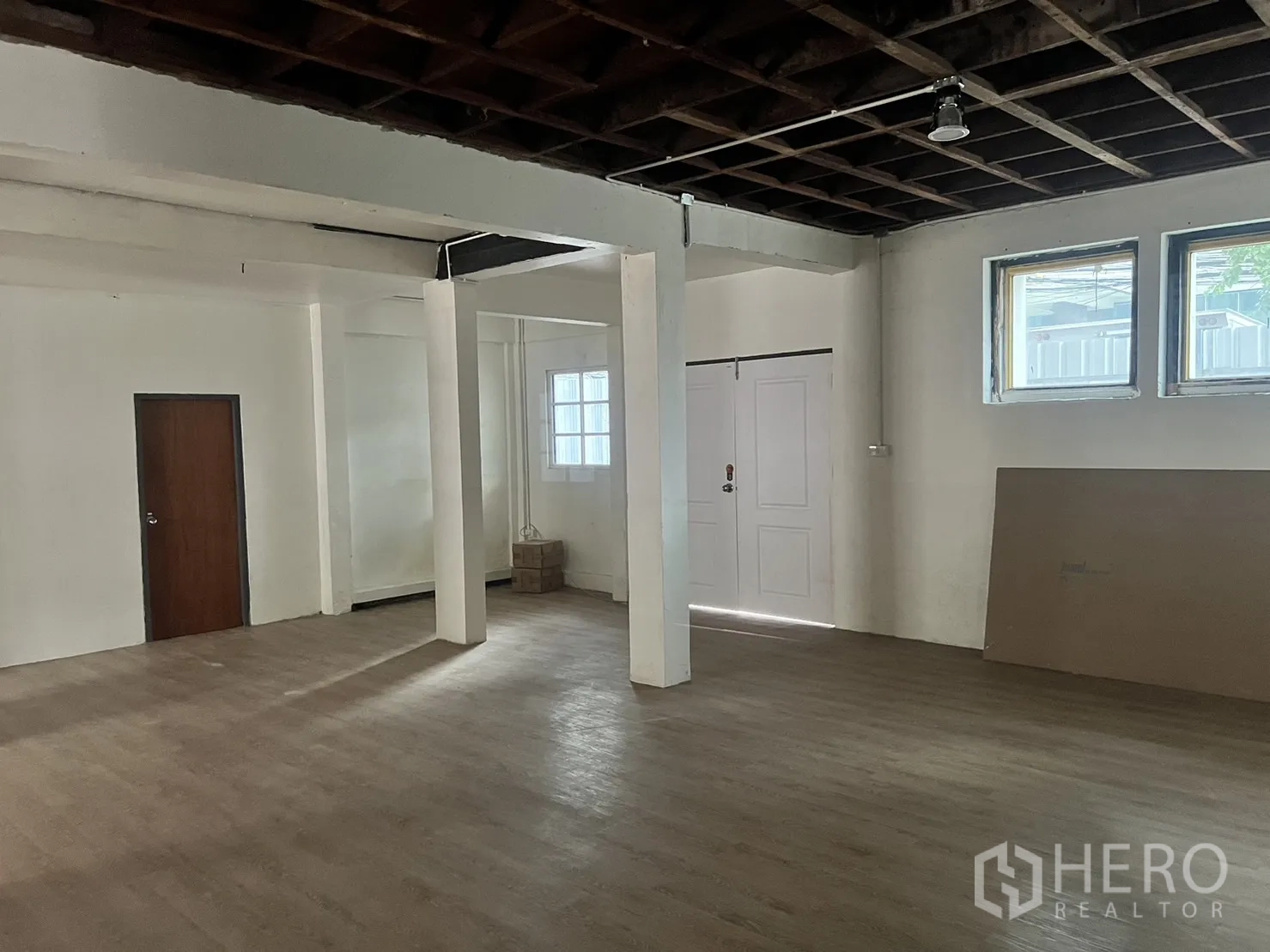 零售空间 出租在Watthana, Bangkok - 开放式零售室内，立柱、木纹地面与外露天花，靠近 Asok。