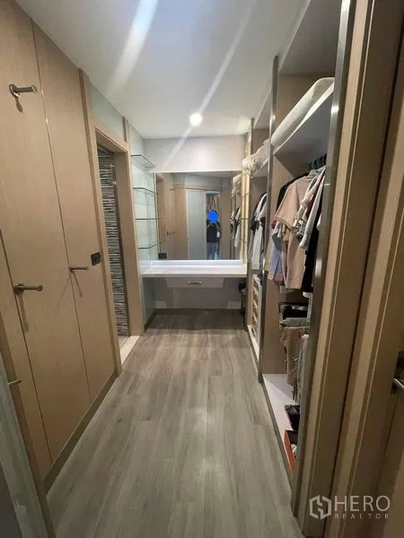 Condominium for rent in Sathon, Bangkok - Walk-in closet corridor with built-in wardrobes, open shelving and a dressing table with mirror.