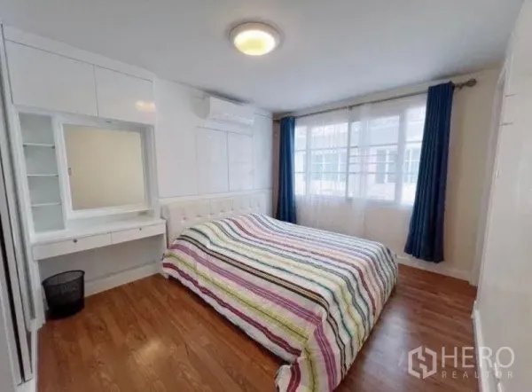 ทาวน์เฮาส์ ให้เช่าในPhra Khanong, Bangkok - ห้องนอนพร้อมหน้าต่างบานกว้าง ม่านสีน้ำเงิน ตู้เสื้อผ้าบิวท์อิน โต๊ะเครื่องแป้ง และพื้นไม้