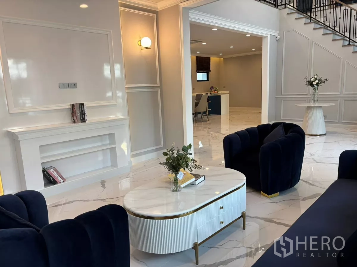 独立式住宅 出租在Bang Phli, Samut Prakan - 客厅配海军蓝沙发、白色装饰墙与大理石茶几。