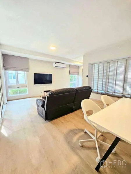 Detached House for rent or sale in Prawet, Bangkok - Open-plan living and dining area with wall-mounted TV and wide windows.