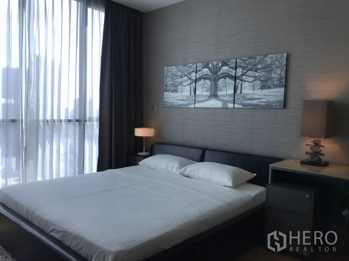 Condominium for rent in Watthana, Bangkok - Primary bedroom with king bed, textured feature wall and floor-to-ceiling curtains.
