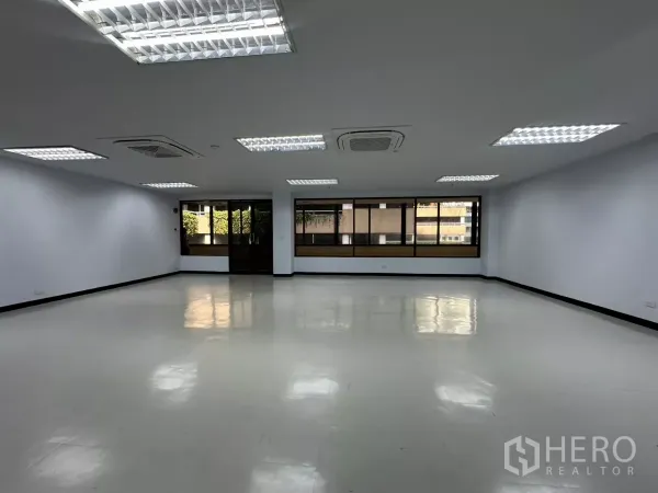 Office Space for rent - Open office area with tiled floors, multiple ceiling lights and wide exterior-facing windows.