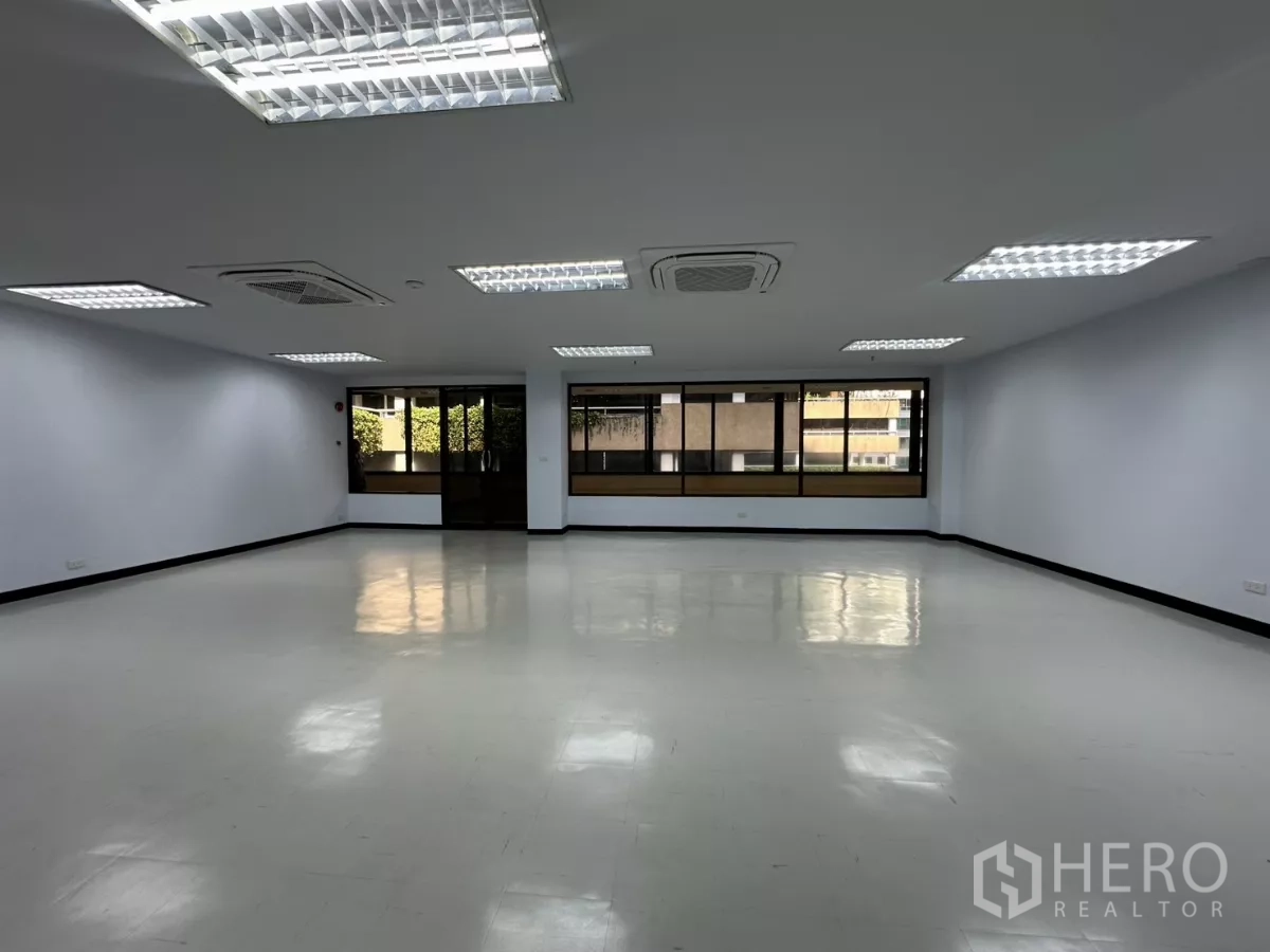 Office Space for rent - Open office area with tiled floors, multiple ceiling lights and wide exterior-facing windows.