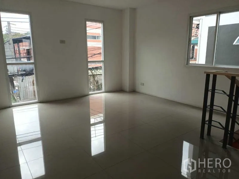 Shophouse for sale in Bueng Kum, Bangkok - Corner room with large windows providing natural light and a glossy tiled floor.