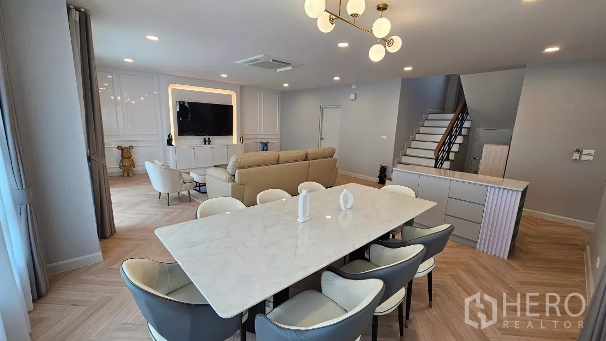 Detached House for rent or sale in Bang Phli, Samut Prakan - Dining space with a marble table and modern chandelier facing the living area and staircase.