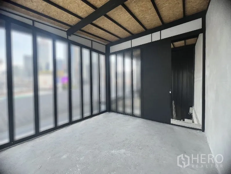 零售空间 出租在Watthana, Bangkok - 转角空间配落地半透玻璃与黑色钢框，裸露天花和水泥地面