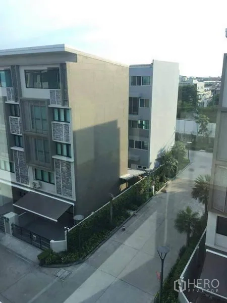 Townhouse for sale in Yan Nawa, Bangkok - View from the home overlooking modern low-rise residences and a quiet private road with trees.