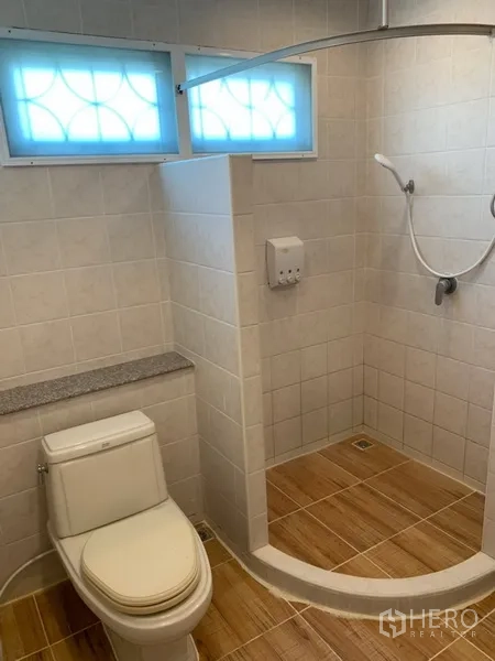 Detached House for rent in Khlong Toei, Bangkok - Bathroom with walk-in shower, curved partition track, frosted windows and wood-look floor tiles.