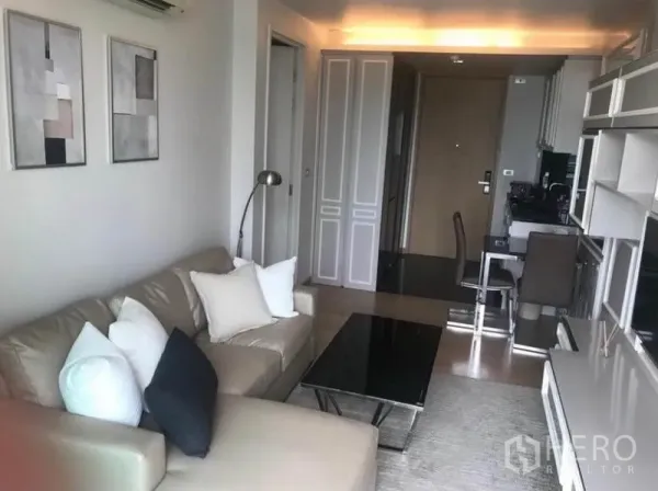 公寓 出租在Watthana, Bangkok - 开放式起居与用餐区，设沙发、电视柜、紧凑厨房和入户走廊。