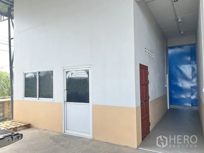 Warehouse for rent in Lat Krabang, Bangkok - Service corridor beside the office with exterior doors and light two-tone walls.