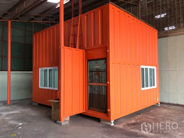 Warehouse for rent in Min Buri, Bangkok - Bright orange container-style office inside the warehouse with windows and a glass entry door.