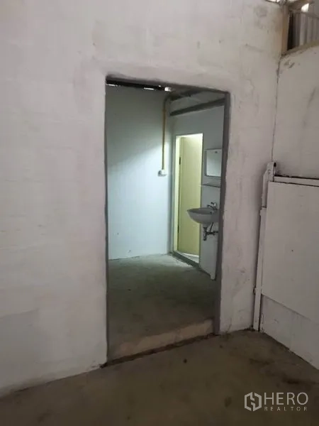 Warehouse for rent in Suan Luang, Bangkok - Entrance to restroom area with wall-mounted sink inside the warehouse.