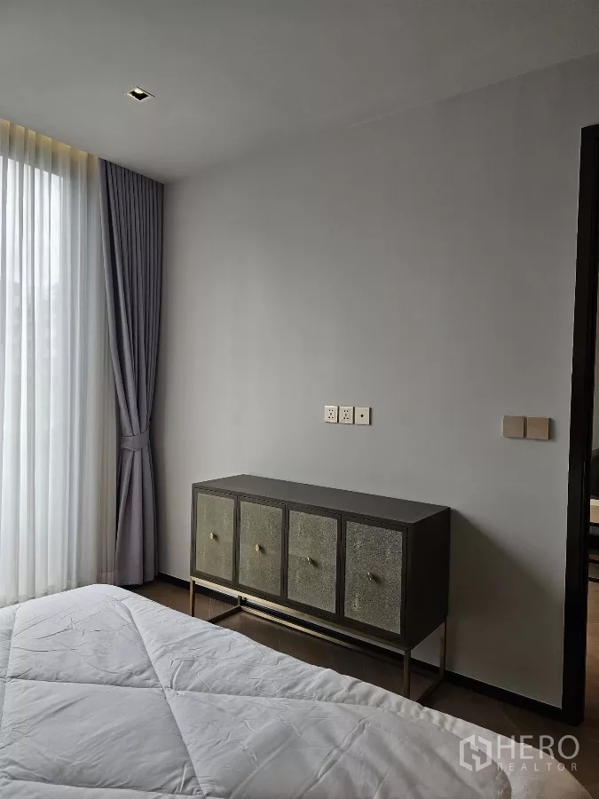 公寓 出租在Watthana, Bangkok - 卧室墙面配时尚矮柜与柔和灯光。