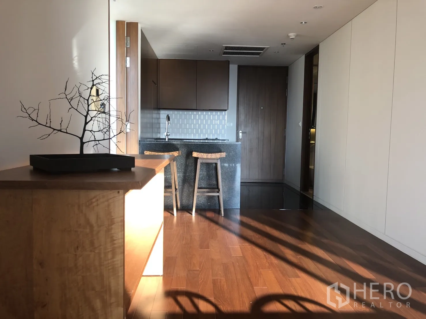 公寓 出租在Pathum Wan, Bangkok - 紧凑厨房，石质中岛吧台、吧椅、瓷砖防溅板与内置柜体