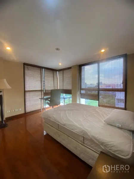 公寓 出租或出售在Watthana, Bangkok - 转角卧室，环绕大窗、木地板、书桌与城市景观