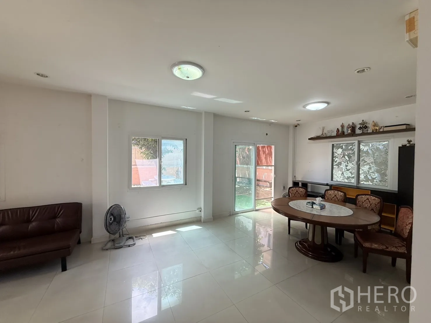 Detached House for rent in Lam Luk Ka, Pathum Thani - Open-plan living and dining space with oval dining table, chairs, and sliding glass door.