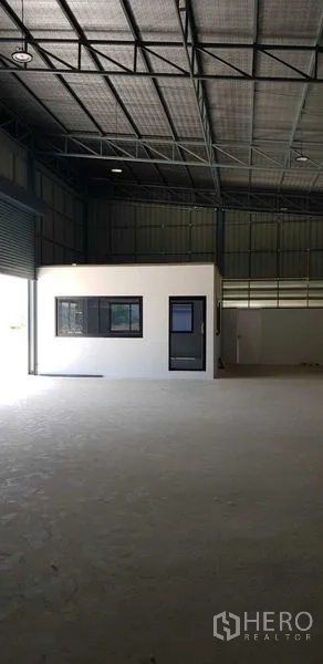 Warehouse for rent in Lat Lum Kaeo, Pathum Thani - Spacious warehouse interior with a high metal roof and a built-in white office unit.
