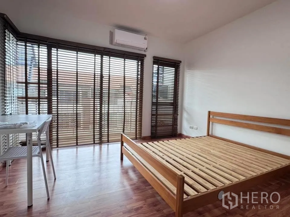 联排别墅 for rent in Phra Khanong, Bangkok - 转角卧室设大窗、木床架与百叶窗。