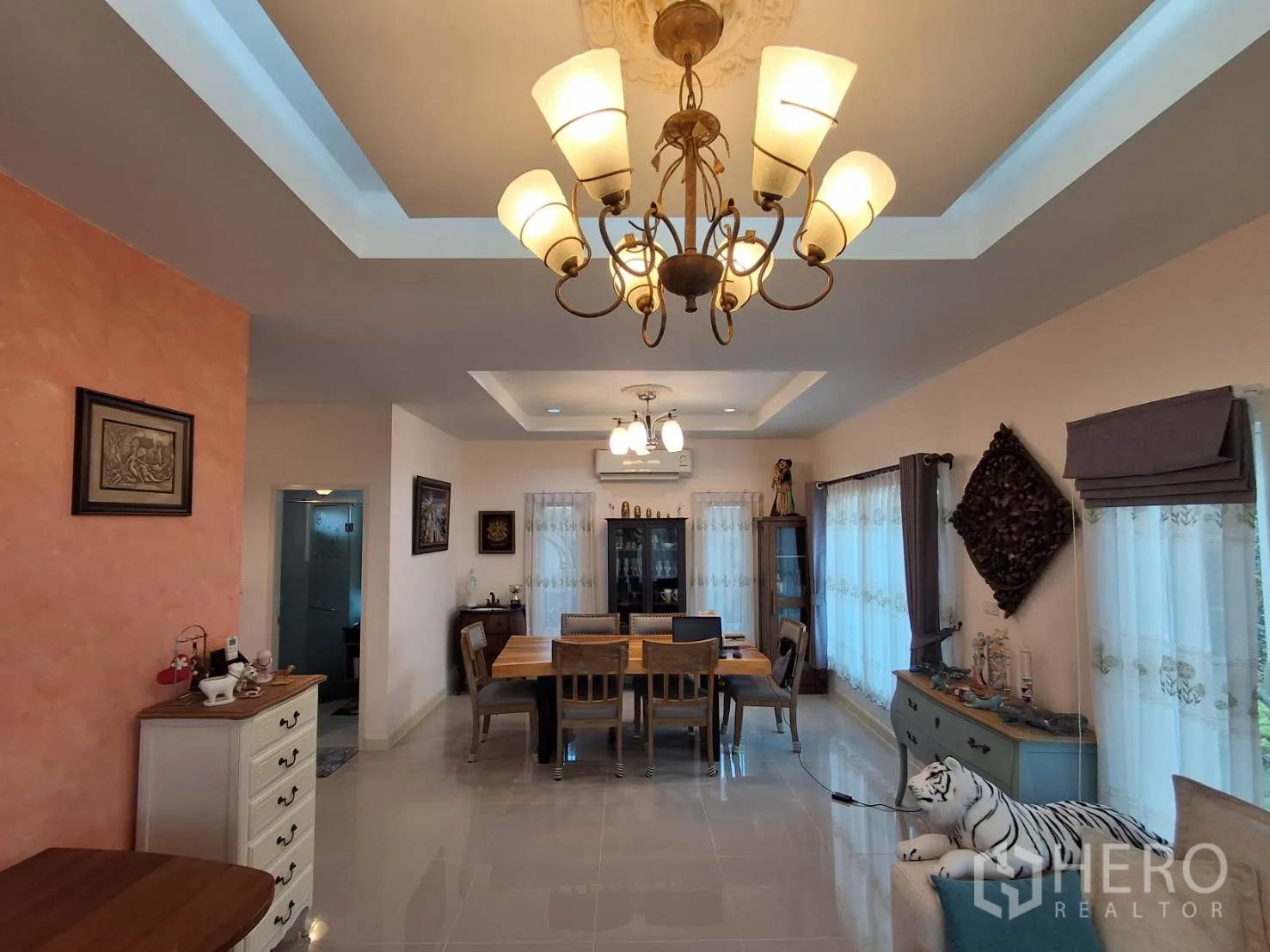 Detached House for rent or sale in Ban Chang, Rayong - Dining area with chandelier, long wooden table and large windows with drapes.
