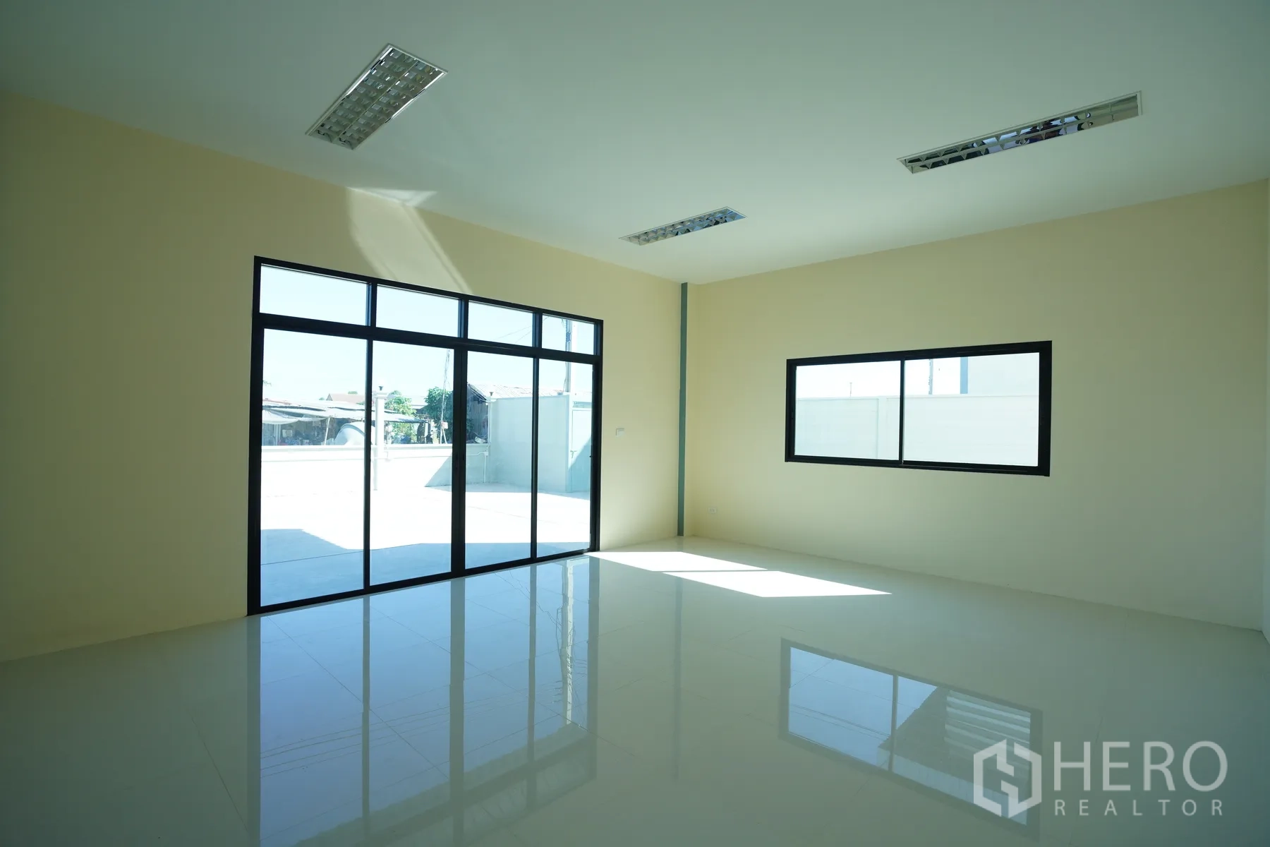 Factory for rent in Mueang Samut Prakan, Samut Prakan - Ground-floor office with large glass doors, tiled flooring, and windows for natural light.