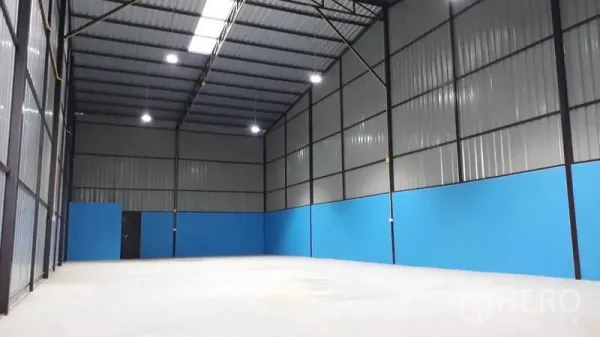 工厂 出租在Khlong Luang, Pathum Thani - 开放式仓储生产空间，墙体高耸，钢桁架与下部蓝色护墙板。