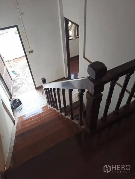 联排别墅 出租或出售在Wang Thonglang, Bangkok - 实木楼梯与经典扶手通向一层。