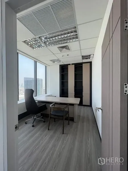 Office Space for rent in Huai Khwang, Bangkok - Private office with executive desk, large windows and built-in shelving overlooking the Bangkok skyline.