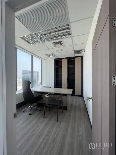 Office Space for rent in Huai Khwang, Bangkok - Private office with executive desk, large windows and built-in shelving overlooking the Bangkok skyline.