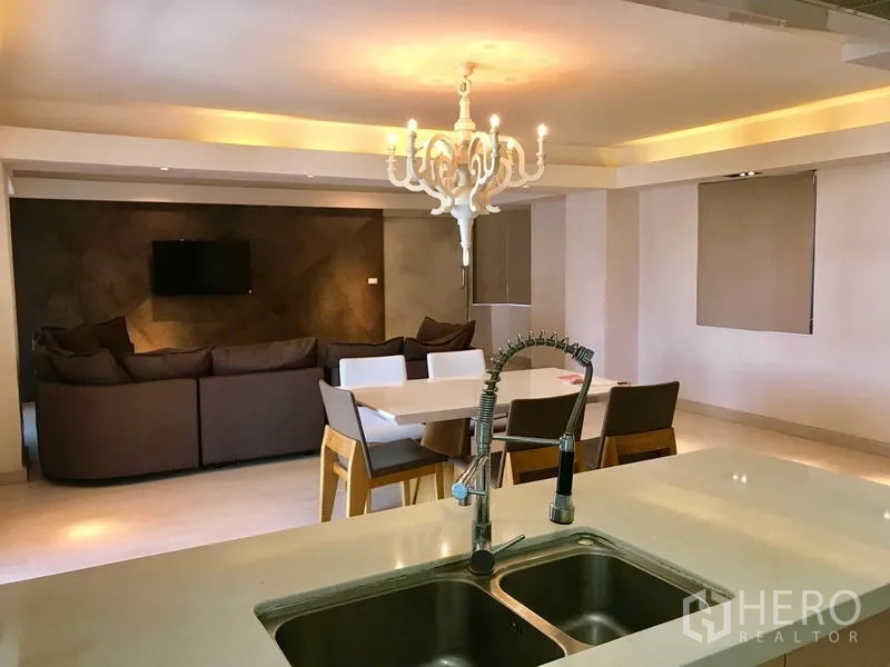 Condominium for rent or sale in Watthana, Bangkok - Modern kitchen island with double sink and pull-out faucet overlooking the dining and living space.