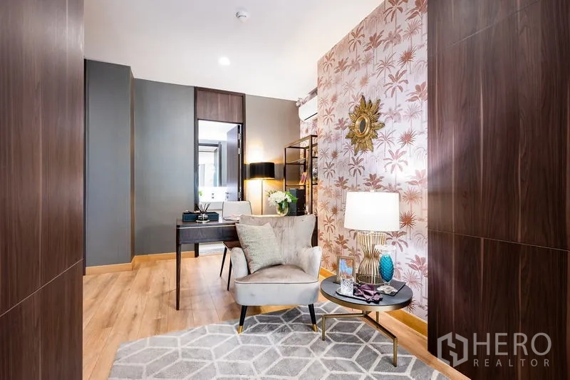 Condominium for sale - Reading nook and study area with armchair, side table and patterned wallpaper.