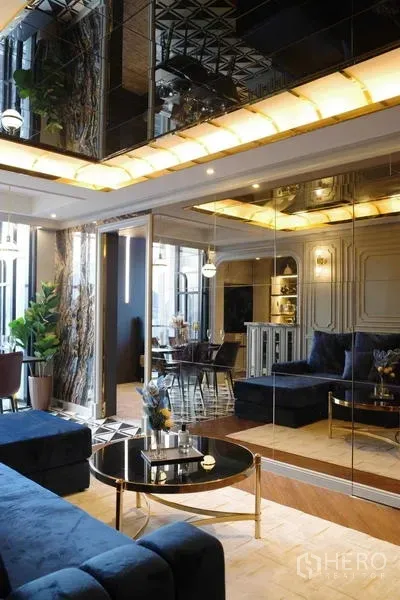 คอนโด ขาย - เลานจ์โซฟากำมะหยี่สีน้ำเงิน ผนังกระจก และไฟฝ้าเพดานโทนอุ่น