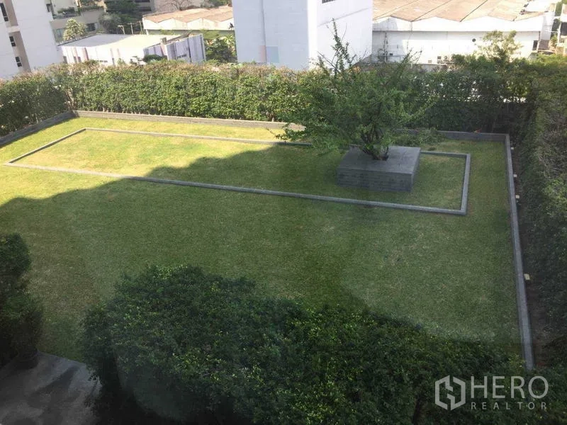 คอนโด ให้เช่า - สวนส่วนกลางตกแต่งเรียบร้อย มีต้นไม้ตรงกลางและแนวรั้วพุ่ม มุมมองจากด้านบน