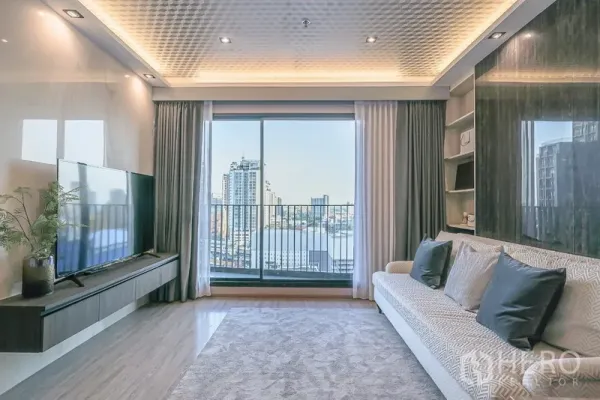Condominium for rent in Watthana, Bangkok - Bright living room with floor-to-ceiling glass doors opening to a balcony and city skyline view.