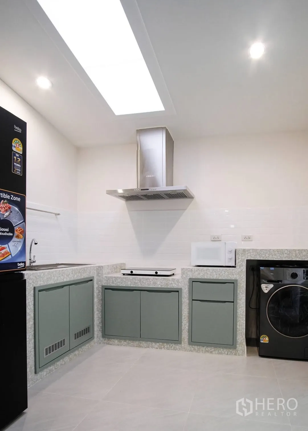 Townhouse for rent in Bang Phli, Samut Prakan - Bright kitchen with hob, range hood, fridge, microwave, and washing machine.