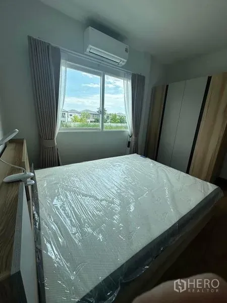 Detached House for rent in Bang Phli, Samut Prakan - Cozy bedroom with bed, wardrobe, curtains, and air conditioner under a wide window.