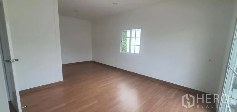 Detached House for rent in Nonthaburi - Spacious bedroom with wood laminate flooring and white walls in Pak Kret, Nonthaburi.