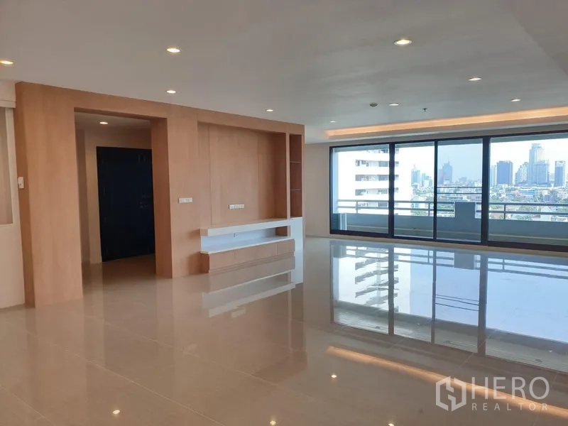 Condominium for rent in Watthana, Bangkok - Spacious living room with glossy tile floors, built-in media wall and full-height sliding doors opening to a balcony with city skyline views.