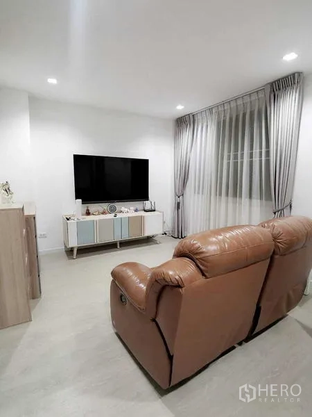 Home Office for rent or sale - Alternate angle of the TV lounge with recliner and full-height curtains.