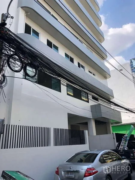 办公空间 出租在Bang Rak, Bangkok - 建筑侧立面，可见路边停车与高架电缆。