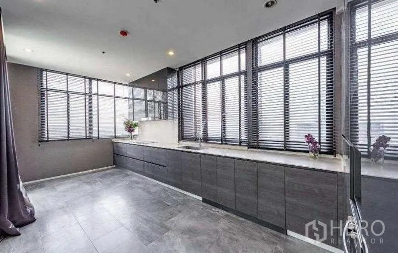 Condominium for rent - Modern linear kitchen with grey cabinetry, stone countertops and window blinds.